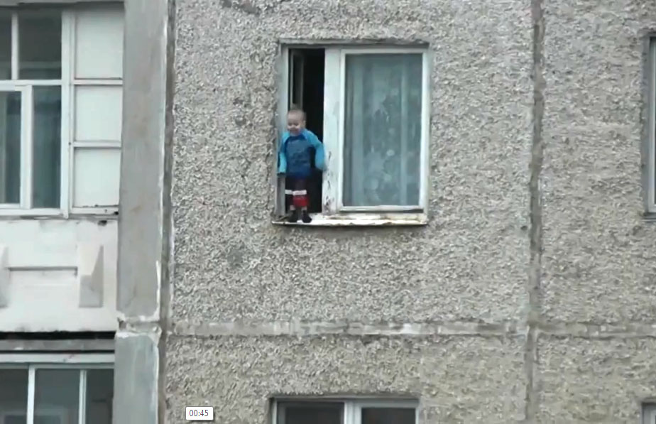 Un enfant joue sur le rebord d’une fenêtre au huitième étage